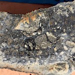 Catastrophic, milled, intrusive clast with black matrix cement tourmaline breccia. Catastrophic crackle tourmaline breccia texture.